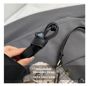 Detail view of black adjustable strap with plaid fabric and cute plush bear charm decoration