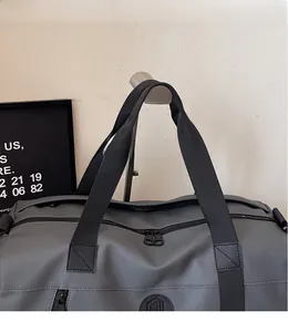 Close-up of durable reinforced black handles and zippers on a gray travel sports bag