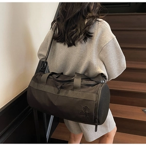 Vue détaillée du sac de sport cylindrique noir avec poche filet latérale et logo brodé