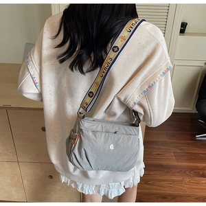 Detail of gray nylon crossbody bag with stylish wide colorful jacquard strap in home setting