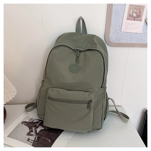 Détail du sac à dos en nylon vert armée avec poche avant zippée et badge logo rond
