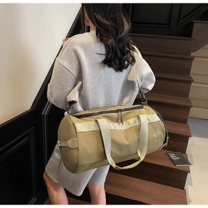 Détail du sac de sport kaki cylindrique avec sangles grises et logo hexagonal stylisé