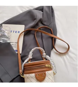 Detail of cream checkerboard bucket bag featuring a silk scarf handle and gold zipper
