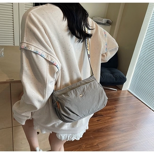 Detail view of grey nylon crossbody bag with colorful woven strap and metal logo buckle