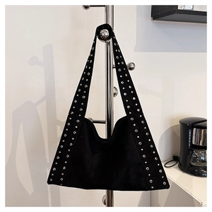 Detail of black suede hobo bag featuring decorative metal eyelets and rocker style shoulder strap