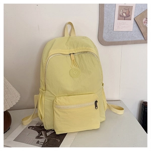 Détail d'un sac à dos décontracté jaune clair avec poche zippée et logo de marque rond
