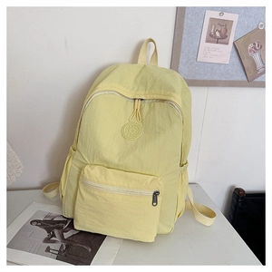 Vue détaillée d'un sac à dos en nylon jaune pâle avec logo sport et multiples poches