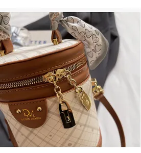 Detail view of the quilted bucket bag with golden zipper chain and silk scarf handle decor