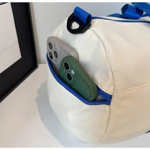 Detail view of the side zipper pocket on a white sports bag holding two smartphones