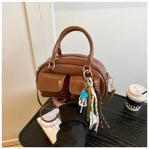 Dettaglio della borsa Boston in pelle lucida marrone con tasche frontali e ciondoli