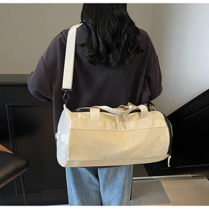 Vue détaillée du sac de sport beige cylindrique avec fermeture éclair noire