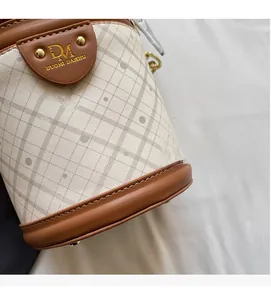 Detail view of woven diamond pattern fabric and brown leather trim on bucket bag