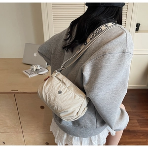 Close-up of beige nylon crossbody bag featuring a wide floral patterned shoulder strap