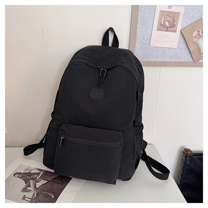 Détail d'un sac à dos léger en nylon noir avec poche zippée et fentes latérales pour bouteilles