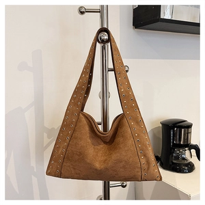 Detail of a brown suede hobo bag with silver rivet studs and a vintage moto design