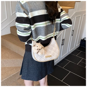 Detailed view of the checkered crescent bag featuring a cute plush pendant on strap