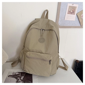 Détail d'un sac à dos en nylon kaki avec texture lisse et logo rond sur bureau blanc