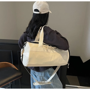 Détail d'un sac de sport beige cylindrique porté à l'épaule par un mannequin