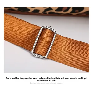 Detail of adjustable brown shoulder strap with silver metal buckle on leopard travel bag