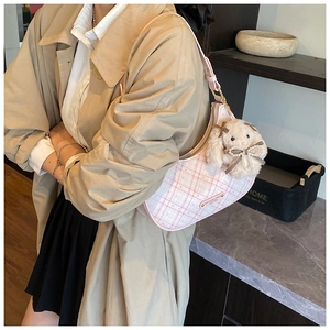 Detail of pink plaid hobo bag featuring a plush bunny charm and logo metal plaque