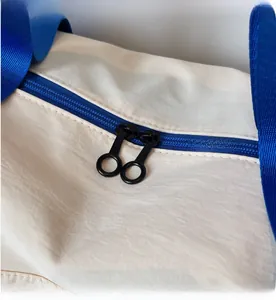 Detail view of the smooth blue zipper and round puller on the beige travel bag