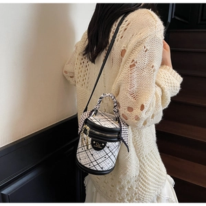 Close-up of quilted bucket bag with golden logo and decorative polka dot scarf handle