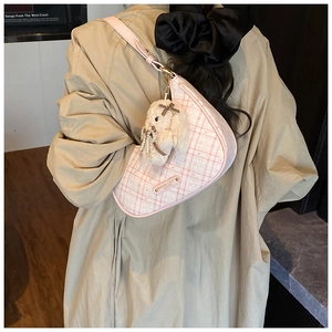 Pink checkered crescent bag with plush puppy pendant shown on model back