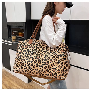 Detail of leopard print travel tote bag featuring brown leather handles and shoulder strap