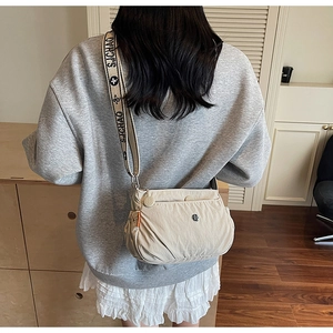 Detail of beige nylon crossbody bag featuring wide branded woven strap and front zipper