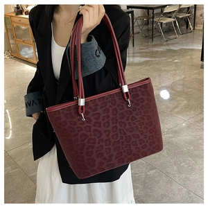 Dettaglio della borsa tote leopardata in pelle scamosciata bordeaux con anelli d'argento
