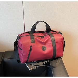 Detail of dark red travel bag with round logo placed on a black leather sofa with book