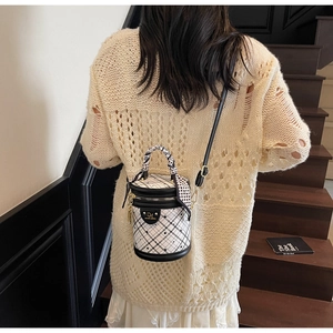 Close-up of a mini cylindrical bucket bag with black lattice pattern and silk scarf handle