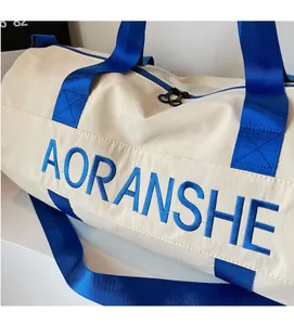 Detailed macro view of cream-colored travel bag with blue handles and embroidered logo