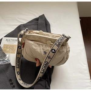 Macro shot of light beige nylon crossbody bag with wide patterned jacquard strap