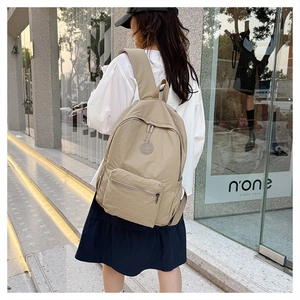 Photo de style urbain d'un sac à dos en nylon kaki porté par un modèle en ville moderne