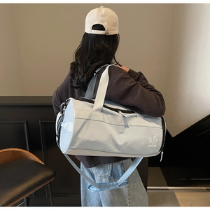 Détail du sac de sport bleu clair montrant la texture, le logo et la bandoulière