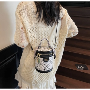 Detail of checkered bucket bag with scarf-wrapped handle on shoulder model