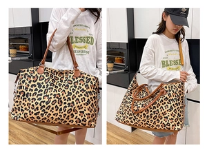 Detail of leopard print travel bag with brown leather handles and adjustable strap
