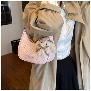Detailed shot of pink plaid crescent shoulder bag with plush bunny charm and logo plaque