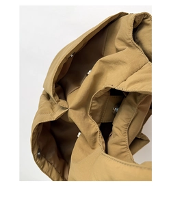 Detail view of khaki bucket bag showing magnetic snap closures and internal compartments
