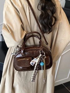 Borsa a tracolla retrò marrone scuro lucido con ciondoli alla moda sopra un trench