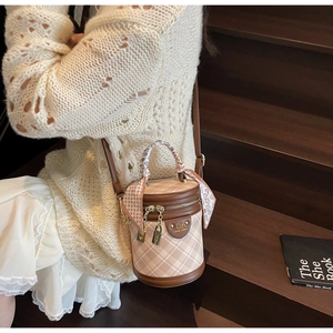 Close-up of a cylinder bucket bag featuring check patterns and silk scarf handle detail