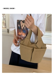 Close-up of a khaki nylon tote bag with double front pockets on a model in daily life