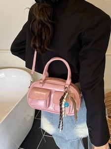 Borsa a bauletto rosa lucida con ciondoli e tasche anteriori indossata da una modella