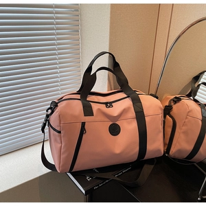 Pink waterproof travel duffel bag with black handles and adjustable shoulder strap