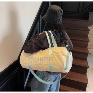 Detail of canvas gym bag showing mint green handles and AORANSHE logo on beige fabric