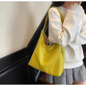 Close-up of a yellow lychee textured leather Hobo bag worn by a model in casual attire