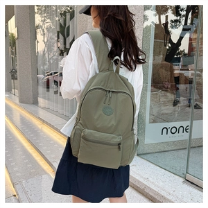 Vue détaillée d'un sac à dos en nylon vert kaki avec plusieurs poches en rue urbaine