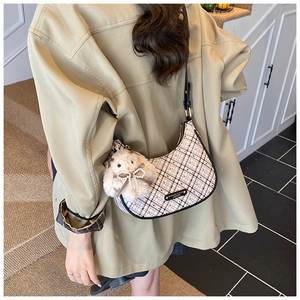 Detail of checkered hobo bag with leather trim and a plush bunny charm on a model