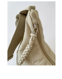Detail of beige nylon dumpling bag featuring woven zipper pull and adjustable strap